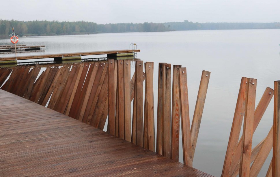Zniszczone drewniane szczeble tworzące palisadę między jeziorem a przystanią.