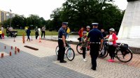 Na zdjęciu widoczne osoby na rowerach oraz stojących przy nich dwóch policjantów wydziału ruchu drogowego.