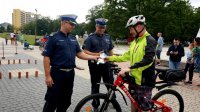 Policjanci z wydziału ruchu drogowego przekazują odblaski oraz ulotki uczestnikowi, który przemierzył przygotowany tor rowerowy.