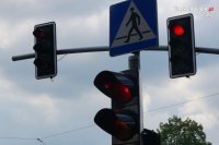 Sygnalizacja świetlna z włączonym światłem czerwonym, widoczny także znak przejścia dla pieszych.