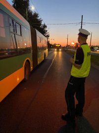 Umundurowany policjant kontroluje autobus miejski.