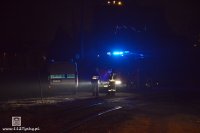 Oznakowany radiowóz policyjny oraz wóz strażacki przy torach kolejowych, jest ciemno