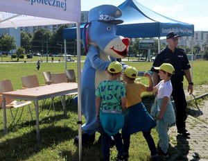 Policyjna maskotka Sznupek z dziećmi oraz policjantem.