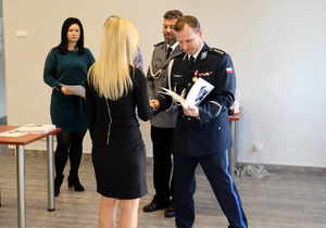 Zastępca Komendanta Miejskiego Policji w Tychach ściska dłoń kobiecie przekazując podziękowania, widoczny inny policjant oraz kobieta.