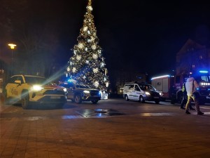 Na zdjęciu choinka oraz stojące obok niej pojazdy, w tym radiowóz Policji, Straży Pożarnej oraz Straży Miejskiej.