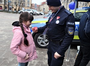Na zdjęciu policjant oraz dziecko podczas obchodów 32. Finału Wielkiej Orkiestry Świątecznej Pomocy.