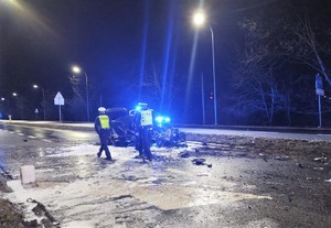 Na zdjęciu umundurowani policjanci obok rozbitego w wypadku drogowym pojazdu.