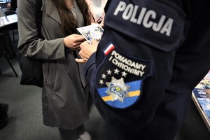 Na zdjęciu policjantka wręczająca ulotkę podczas Tyskich Targów Pracy i Przedsiębiorczości.