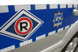 Na zdjęciu bok policyjnego radiowozu z logo ruchu drogowego.