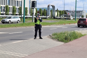 Policjant ruchu drogowego sprawdzający prędkość kierujących laserowym miernikiem prędkości.