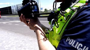 Na zdjęciu umundurowany policjant trzymający ręczny miernik prędkości.